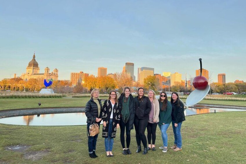 Un grupo de personas de pie en un parque con un horizonte urbano al fondo. 4