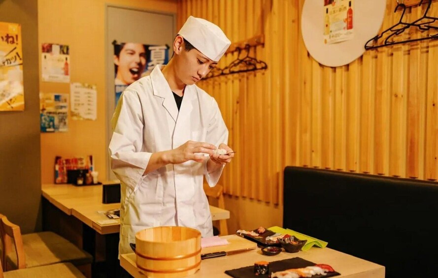 A person in a white chef's coat and hat preparing food at a wooden table with various dishes and utensils. 1