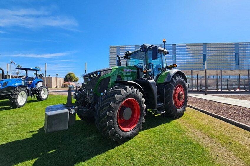 En grön traktor med röda hjul står parkerad på en gräsklädd åker. 3