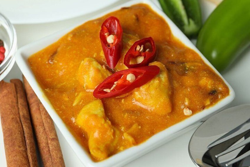 A dish of curry with red chili peppers and cinnamon sticks. 3