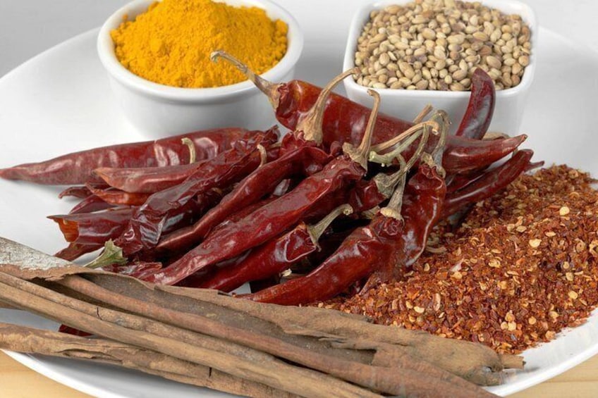 Dried red chili peppers, turmeric powder, and cumin seeds on a white plate. 2