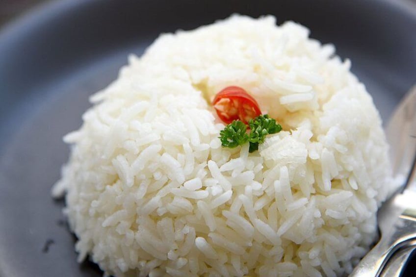 A plate of white rice garnished with a cherry and parsley. 4