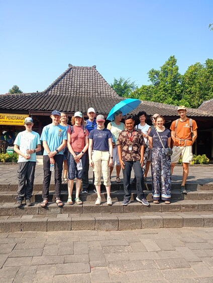 A group of people standing on steps in front of a traditional building with a tiled roof. 2