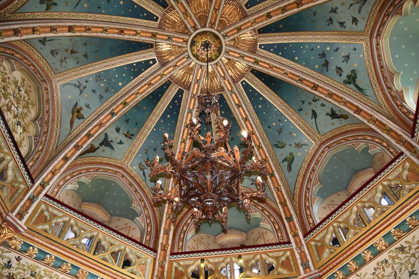A detailed ceiling with a central chandelier, ornate patterns, and star motifs. 3
