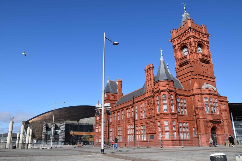 A large red brick building with a clock tower and a modern structure nearby. 4