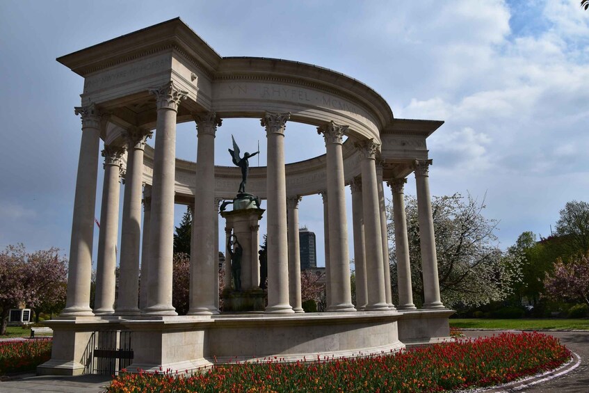 A neoclassical pavilion with columns and a statue in a park. 5