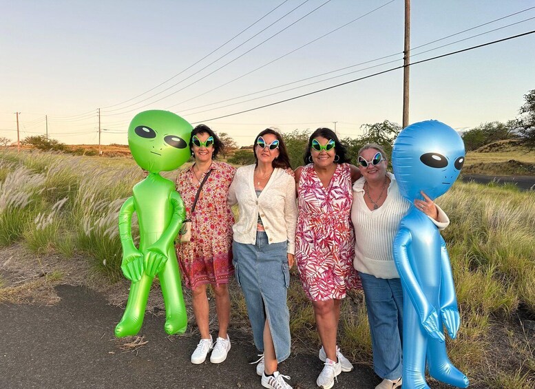 A group of people standing on a road with inflatable alien figures. 2