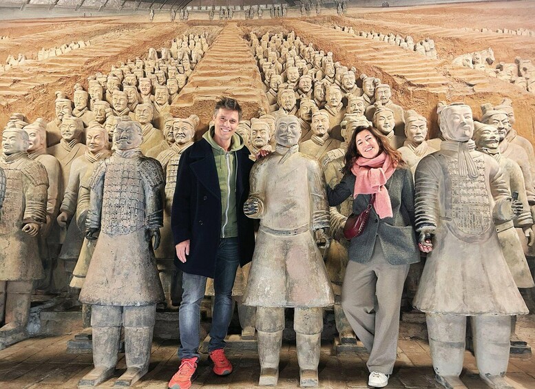 A group of people standing in front of a large number of terracotta warrior statues. 3
