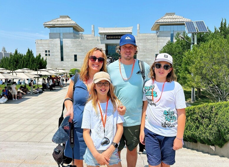 A family in front of a modern building with solar panels, a clear sky, and a crowd in the background. 2