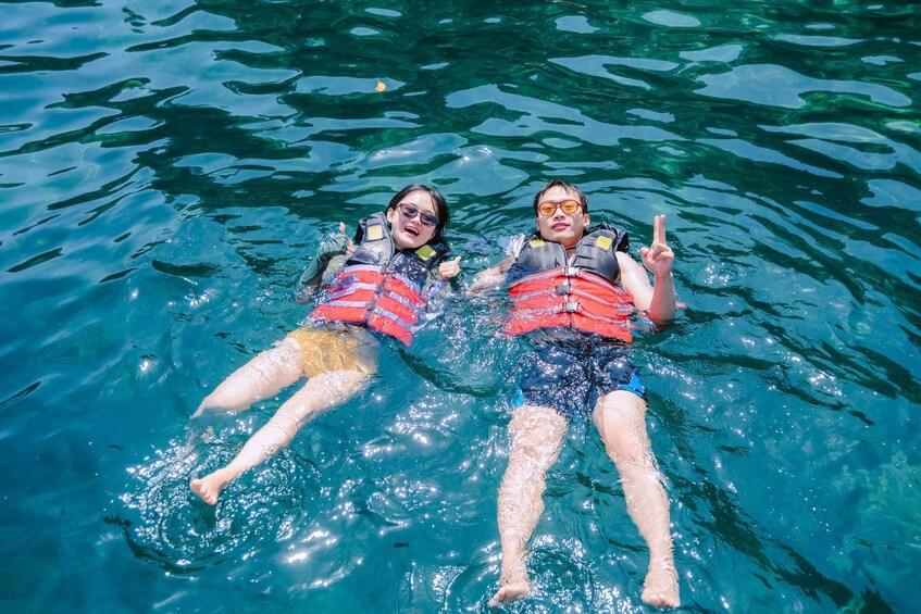 Two people floating on water wearing life jackets. 2
