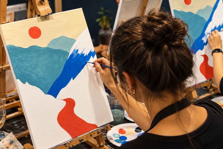 A person painting a landscape with a sun, mountains, and a river. 5