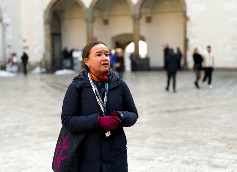 A person standing in a plaza with arches in the background. 5