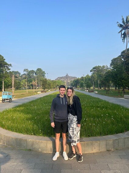 Two people standing in a park with a grassy area and a distant hill. 3