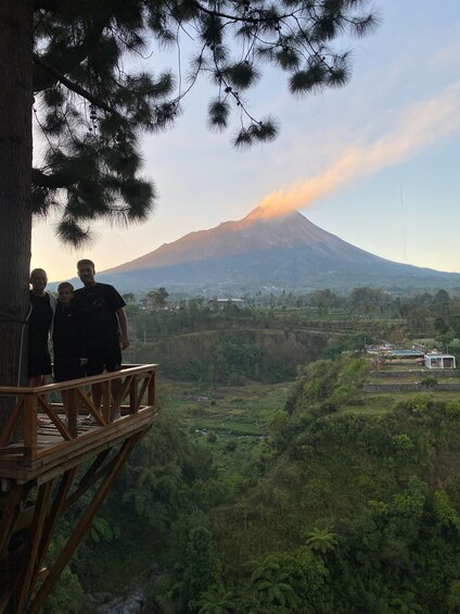 A group of people on a wooden platform overlooking a lush valley with a mountain in the background. 5