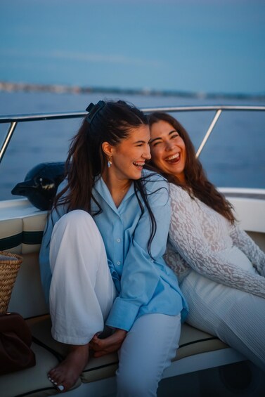 Two people sitting on a boat with a body of water and a distant shoreline in the background. 2