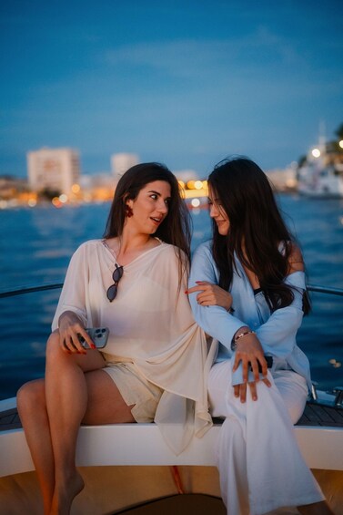 Two people sitting on a boat with a cityscape in the background. 4