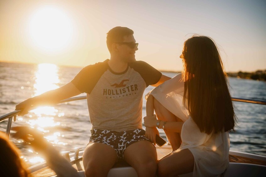 Two people on a boat at sunset with the sun reflecting on the water. 3