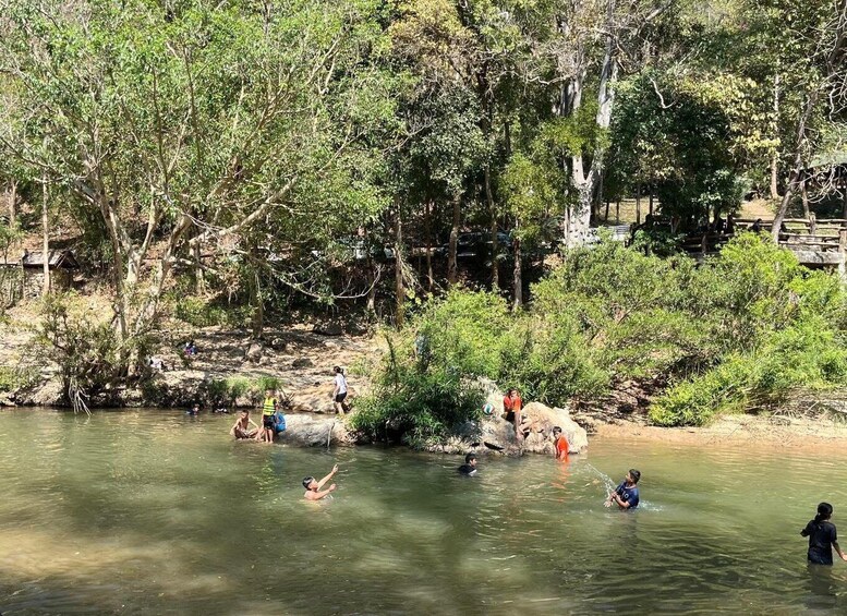 A group of people swimming in a river surrounded by dense trees. 2