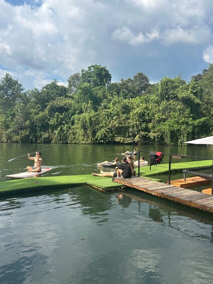 A calm lake with people paddleboarding and sitting on the dock. 5