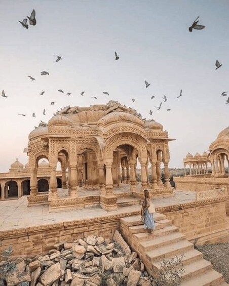 A historic building with intricate architecture and a person walking on the steps. 1