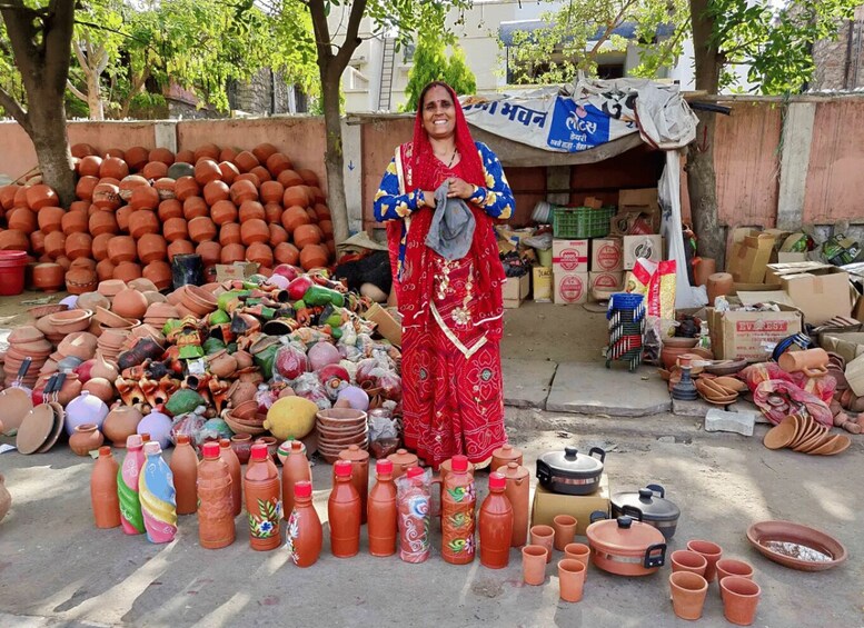 A woman standing in front of a market stall with various pottery items. 3
