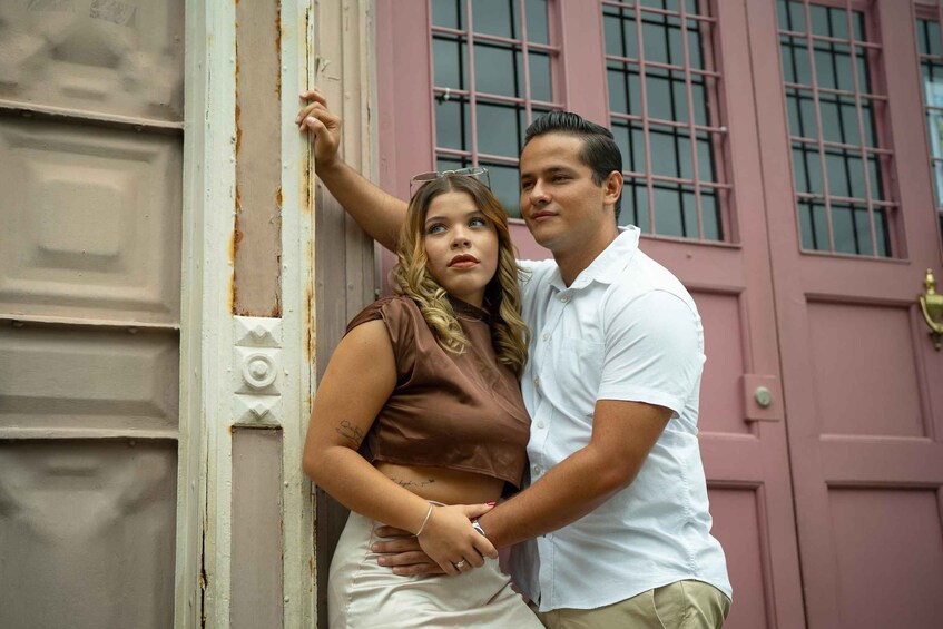 A couple standing in front of a pink building with a white door. 1