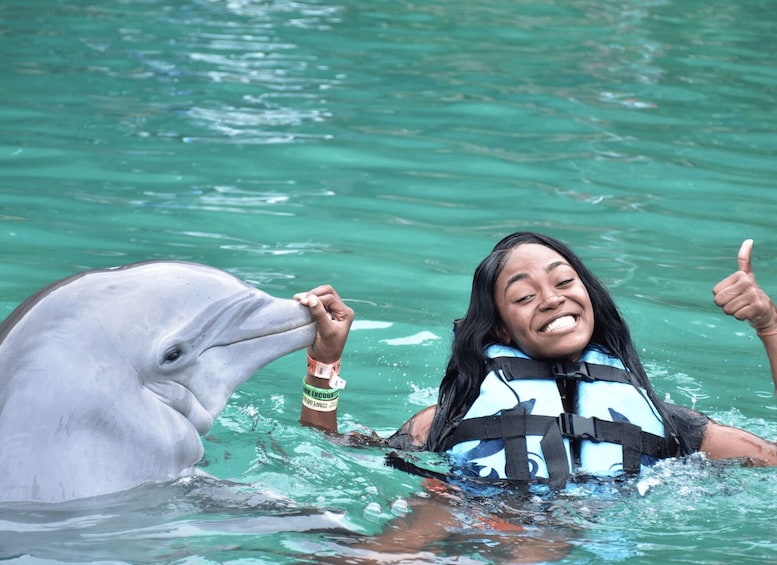 A person in a life jacket interacting with a dolphin in clear water. 2
