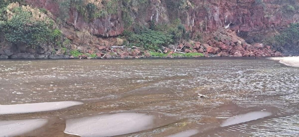 A river with clear water, surrounded by rocky cliffs and sparse vegetation. 4