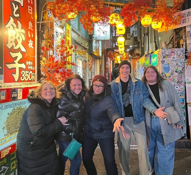 A group of people standing in front of a shop with autumn decorations and a large sign. 4