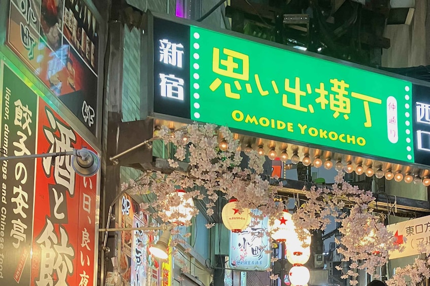 A street sign for Omoide Yokocho restaurant with cherry blossoms overhead. 3