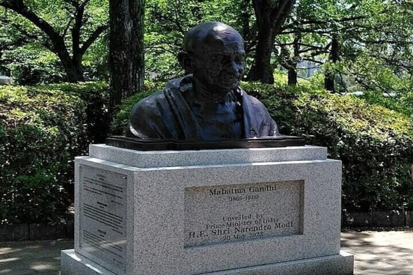 Una statua di Mahatma Gandhi su un piedistallo con una targa. 2