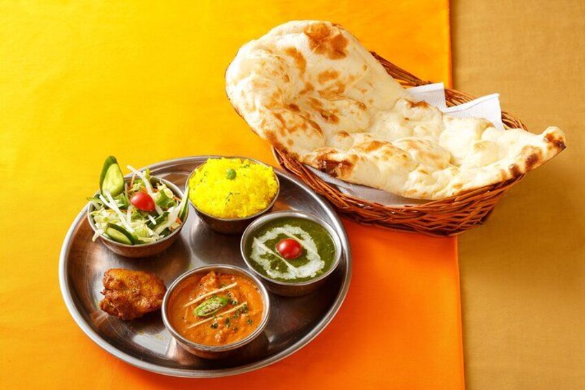 Une assiette de plats indiens, accompagnée de pain naan, comprenant des plats comme le dal, un curry et une salade. 2