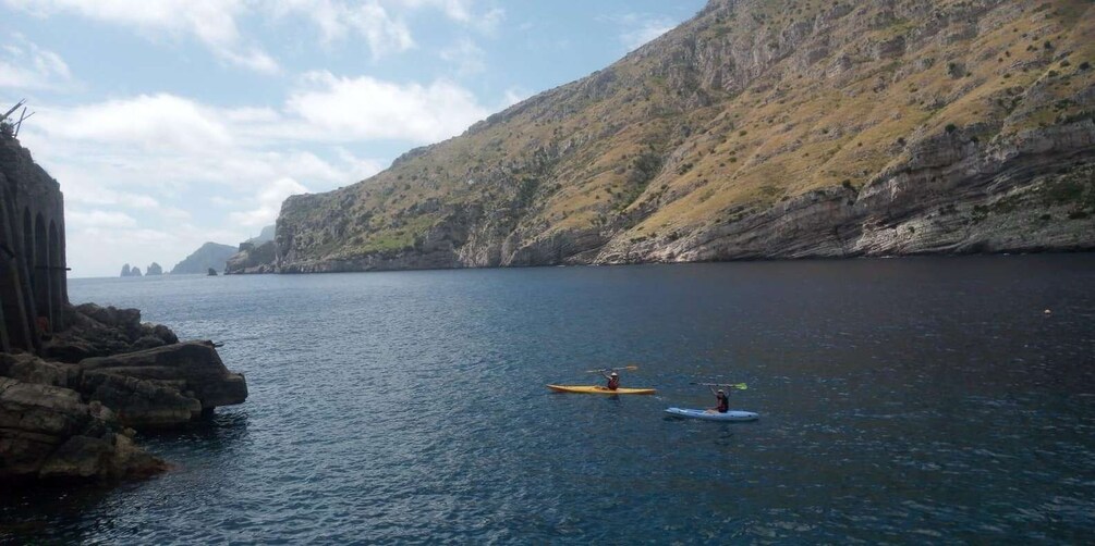 Kayakers on a calm sea with rocky cliffs in the background. 5