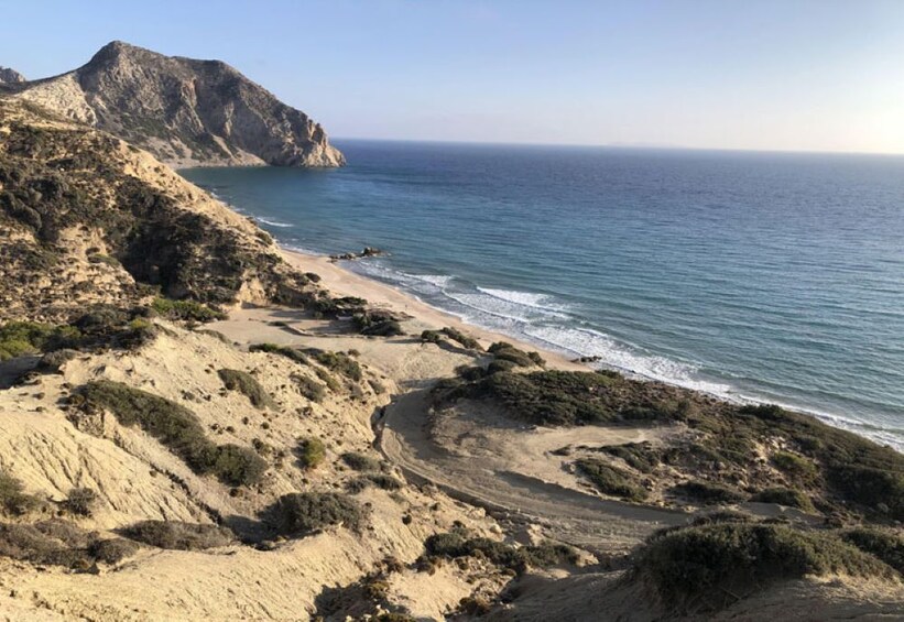 A coastal landscape with a sandy beach, rocky cliffs, and the ocean. 3