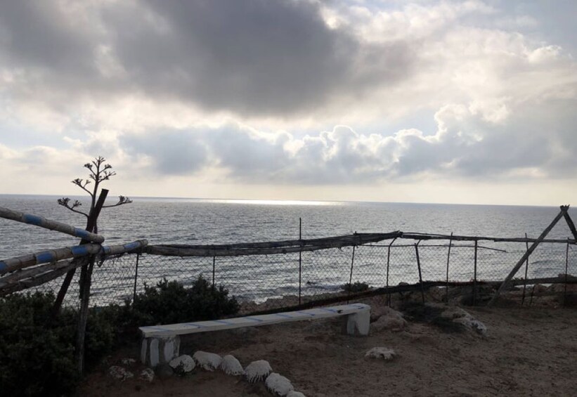 A beach with a wooden fence, a bench, and a rocky shoreline. 5