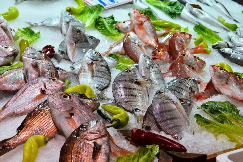 A variety of fresh fish on ice with green lettuce and red chili peppers. 4