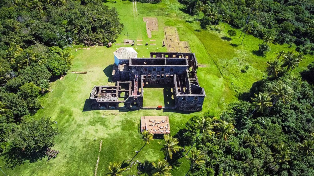 An aerial view of an ancient ruin with multiple structures surrounded by lush greenery. 2