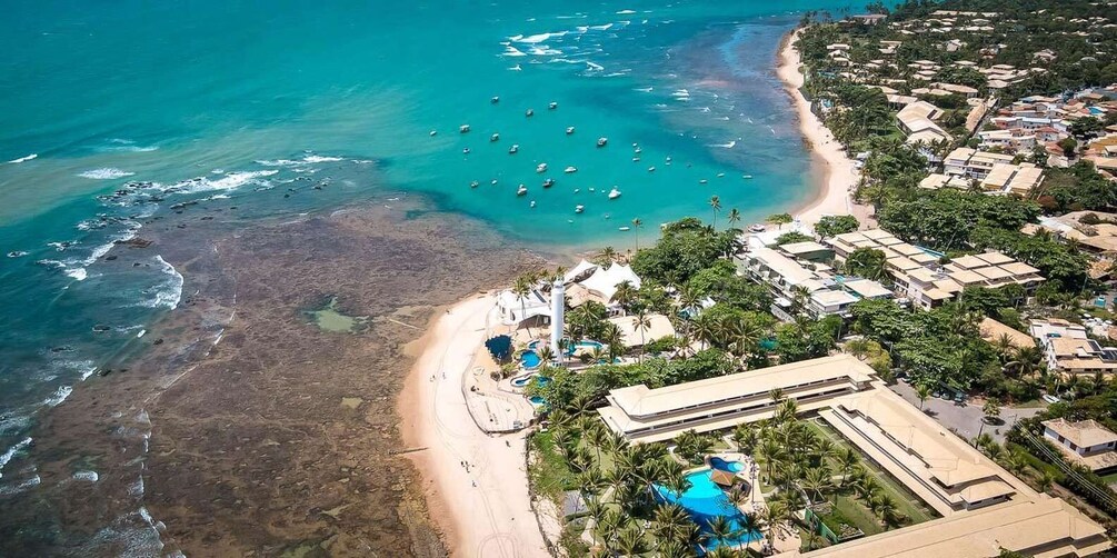 A coastal resort with a beach, clear turquoise waters, and a swimming pool. 1