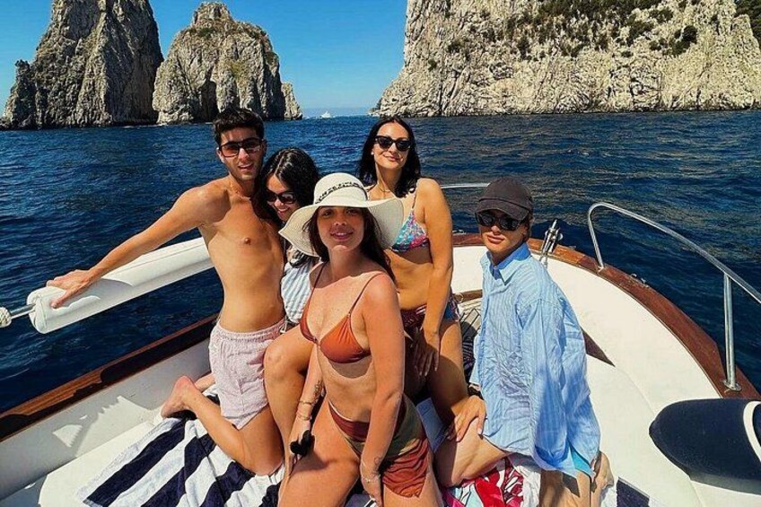 Eine Gruppe von Menschen auf einem Boot, im Hintergrund felsige Klippen. 5
