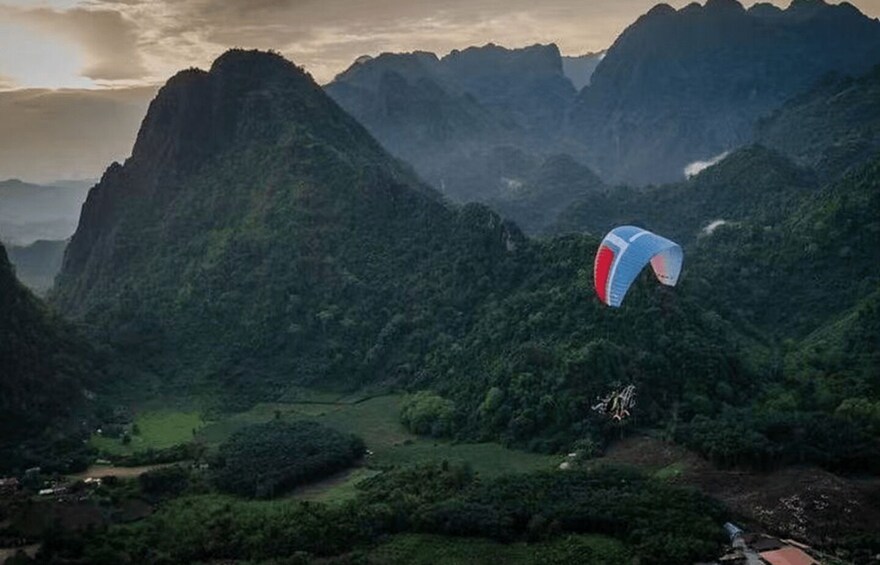 A paraglider flying over a mountainous landscape with lush greenery. 4
