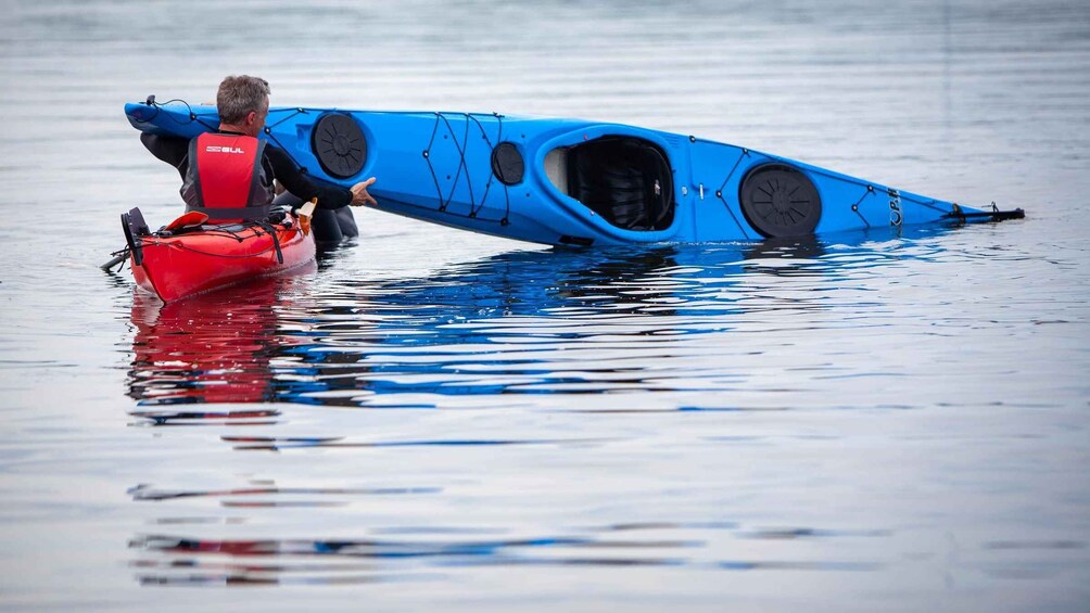 A person in a red life jacket pulling a blue kayak with a unique design. 4