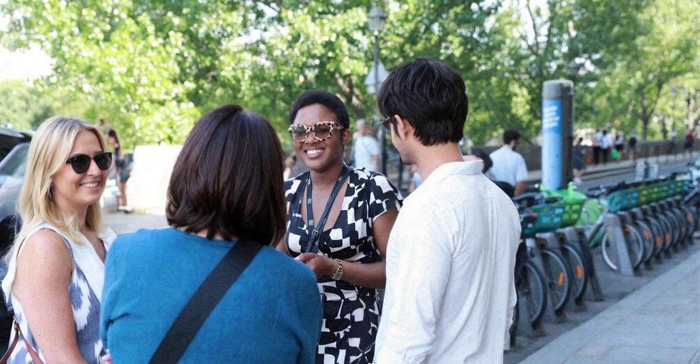 A group of people standing on a sidewalk near a row of parked bicycles. 2