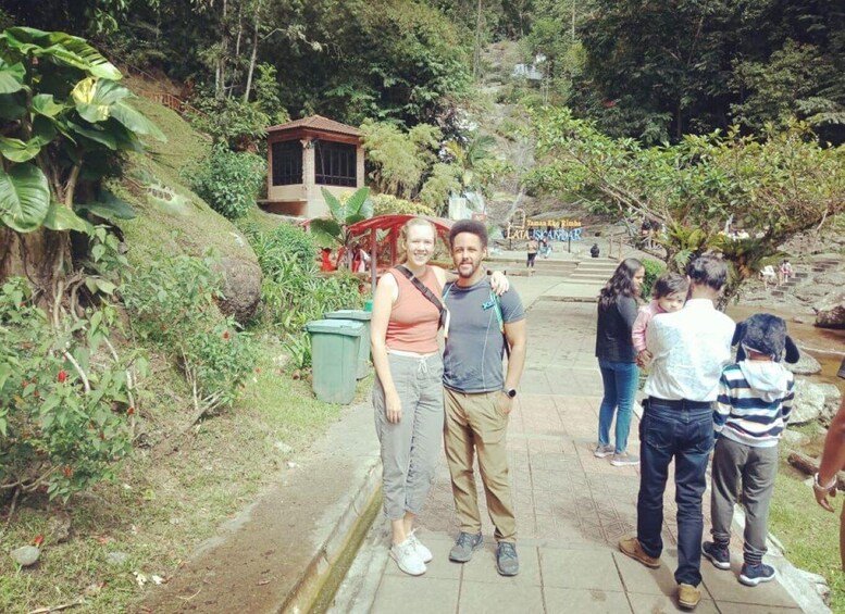 A group of people standing on a stone pathway surrounded by lush greenery and a small building in the background. 3