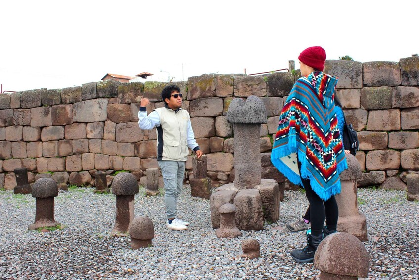 Two people standing in a historical site with stone structures and gravestones. 3