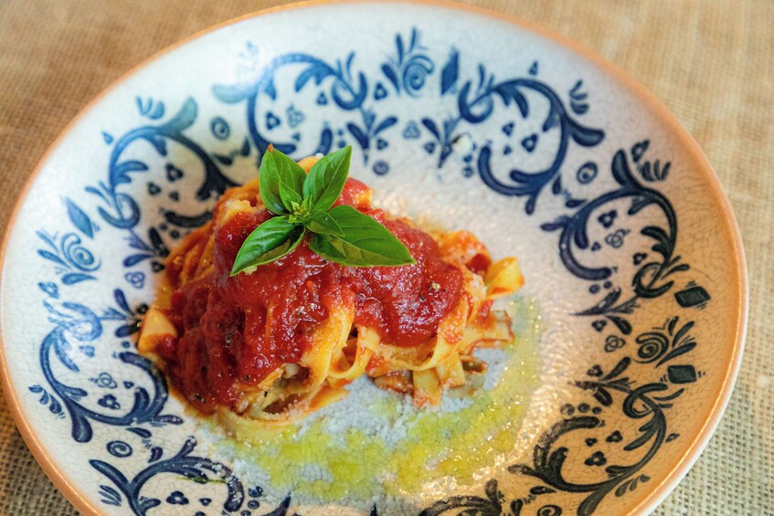 Un plato de pasta con salsa de tomate y una hoja de albahaca como decoración. 2
