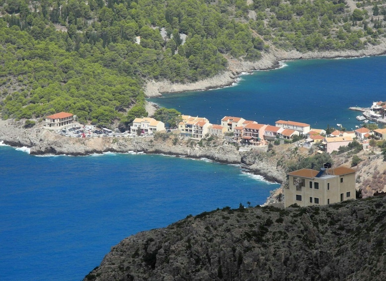 A coastal village with buildings along the shoreline, surrounded by rocky terrain and dense greenery. 4