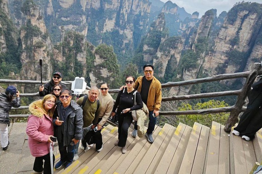 A group of people on a wooden platform with a mountainous landscape in the background. 3