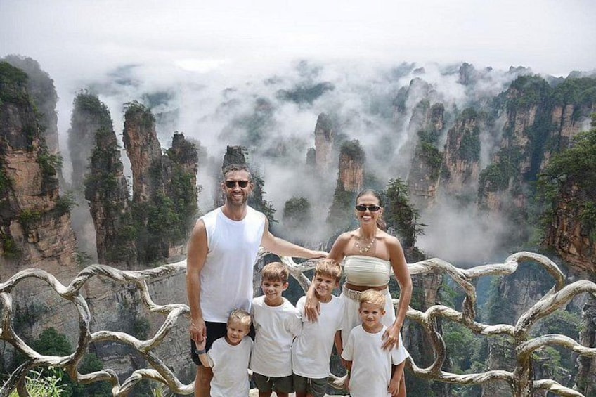 A family standing on a rocky outcrop with a mountainous landscape in the background. 1