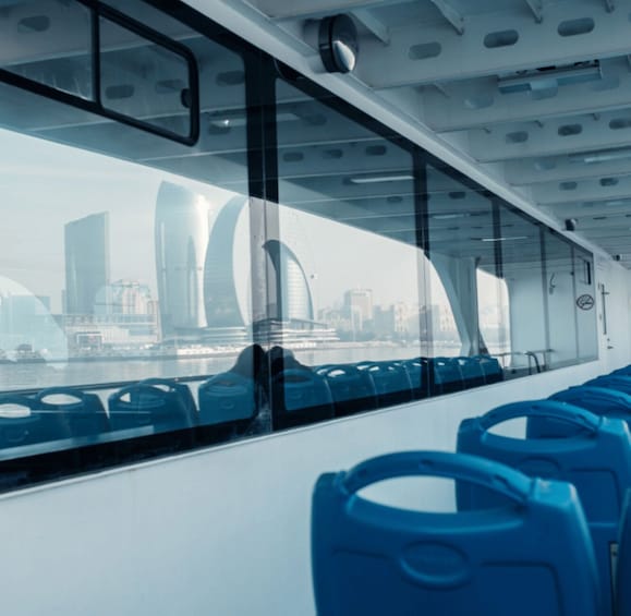 A modern train interior with blue seats and large windows offering a view of a cityscape with tall buildings. 5