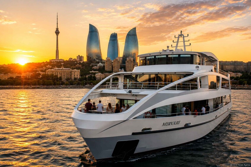A white yacht named 'MIRVARI' on water with a city skyline in the background during sunset. 1